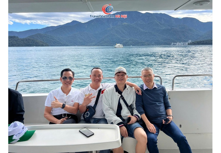 Khách TravelVietnam Hà Nội ngồi trên thuyền giữa Hồ Nhật Nguyệt, phía sau là núi và mặt hồ