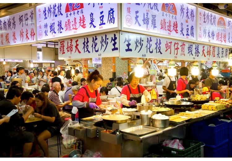 Khu ăn uống trong nhà ở chợ đêm Sĩ Lâm với nhiều quầy và bàn ghế kín khách
