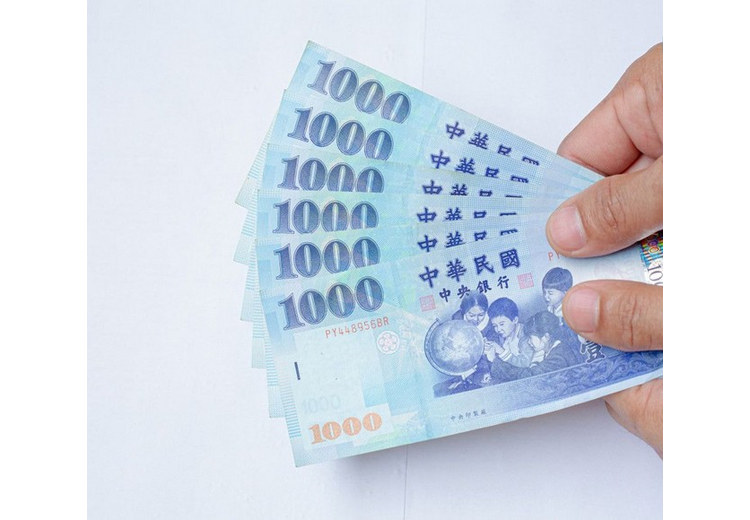 Tay cầm xấp tiền giấy mệnh giá 1.000 Đài tệ